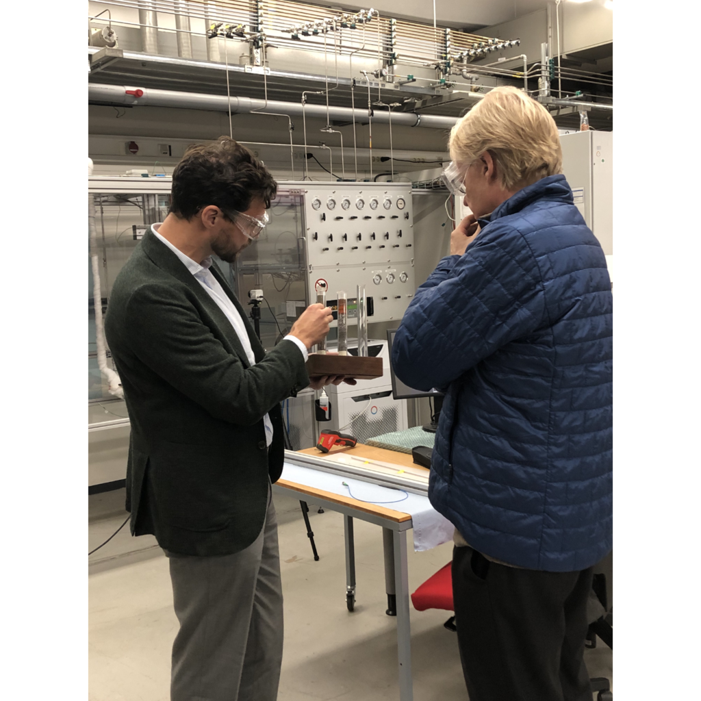 Prof. Dr.-Ing. Gregor D. Wehinger und KIT-Präsident Professor Dr. Jan S. Hesthaven in einem Labor mit technischer Ausstattung im Hintergrund.